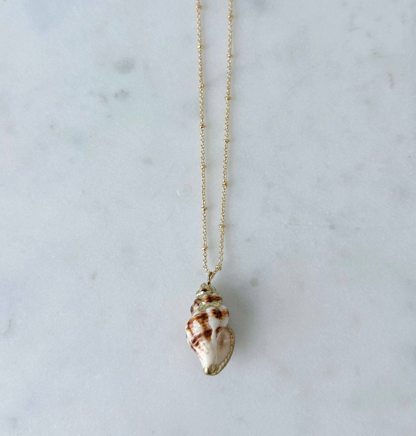 Shell pendant necklace on a marble surface