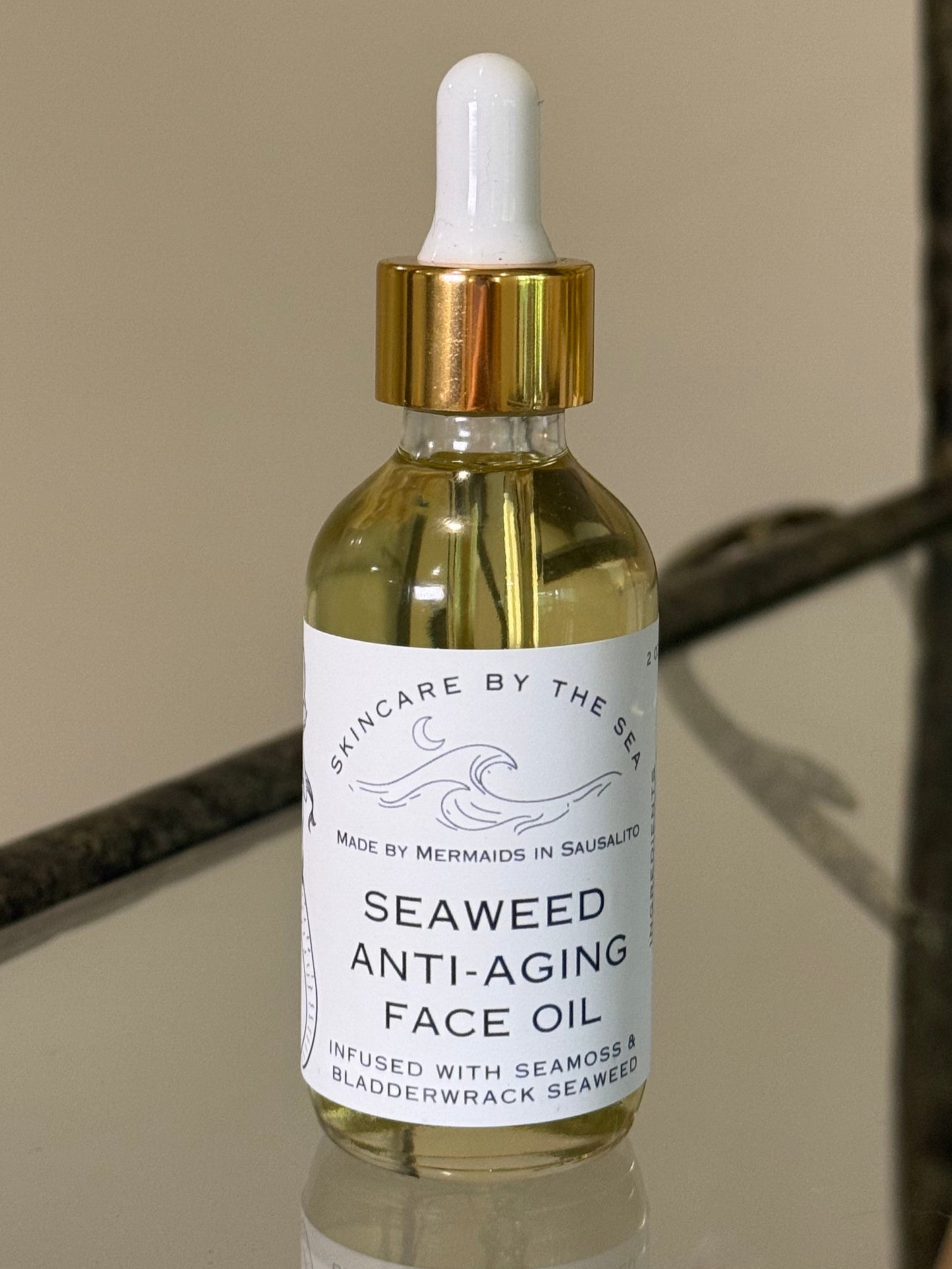 Seaweed anti-aging face oil bottle with dropper on a reflective surface