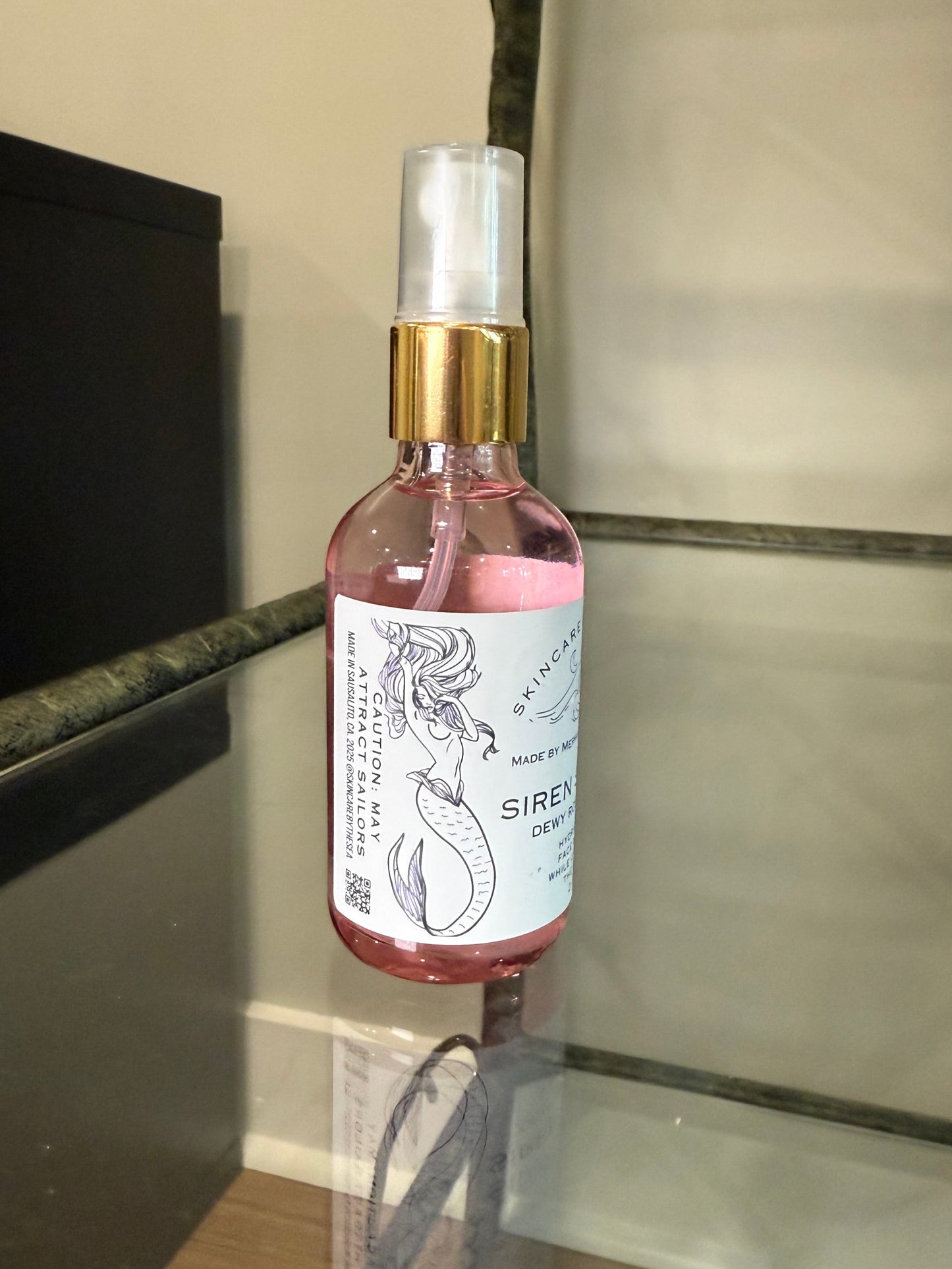 Small bottle of 'Siren Splash' showing the mermaid on the label label on a reflective surface