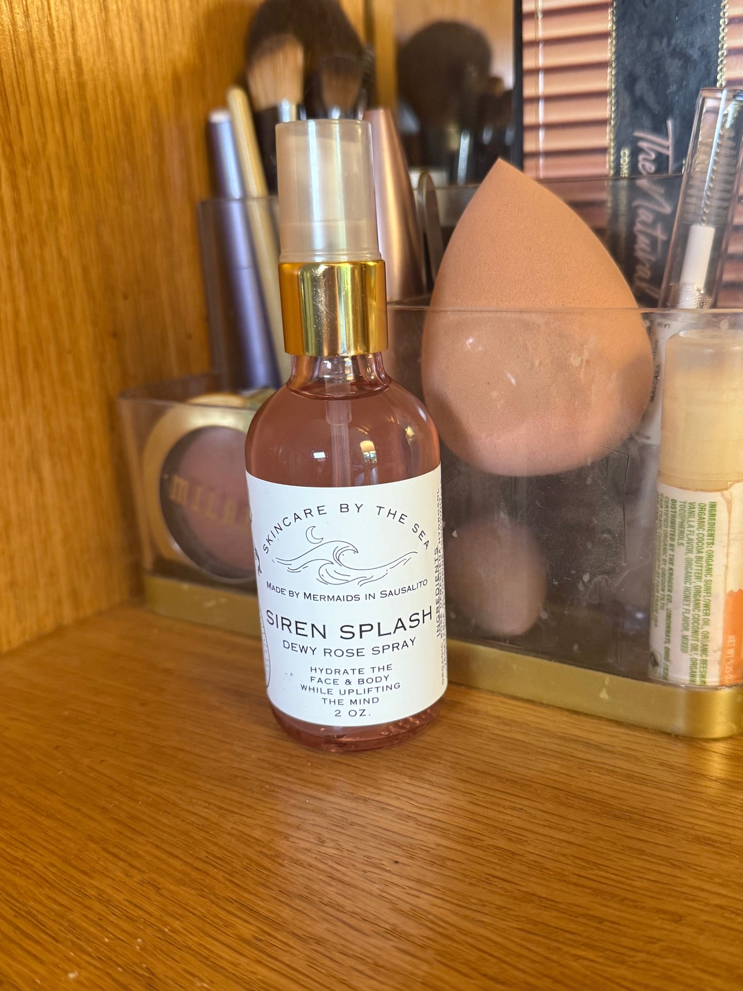 'Siren Splash' Rose spray Makeup setting spray displayed with makeup products.