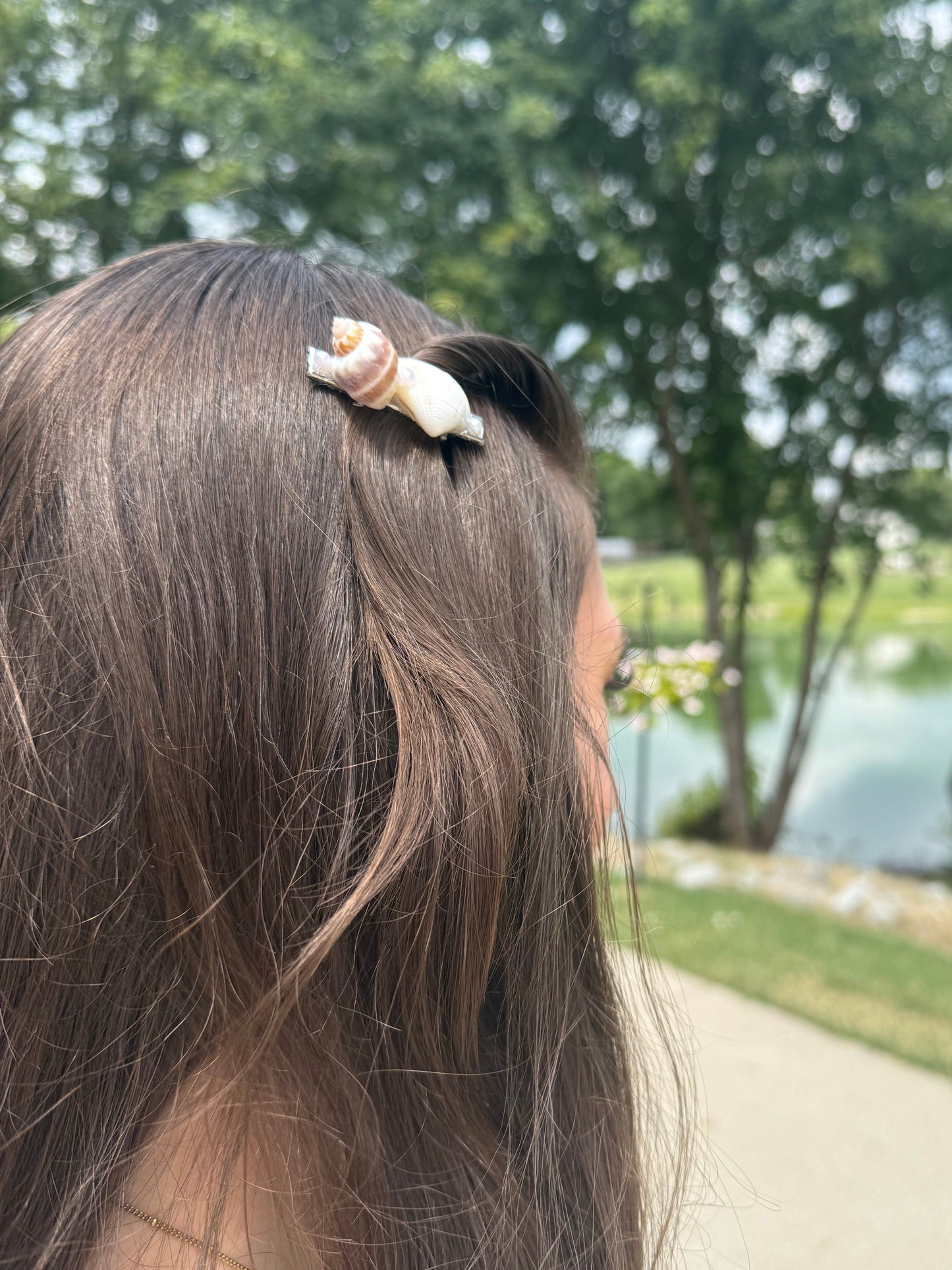 Close-up of a person's head with a seashell hair clip outdoors