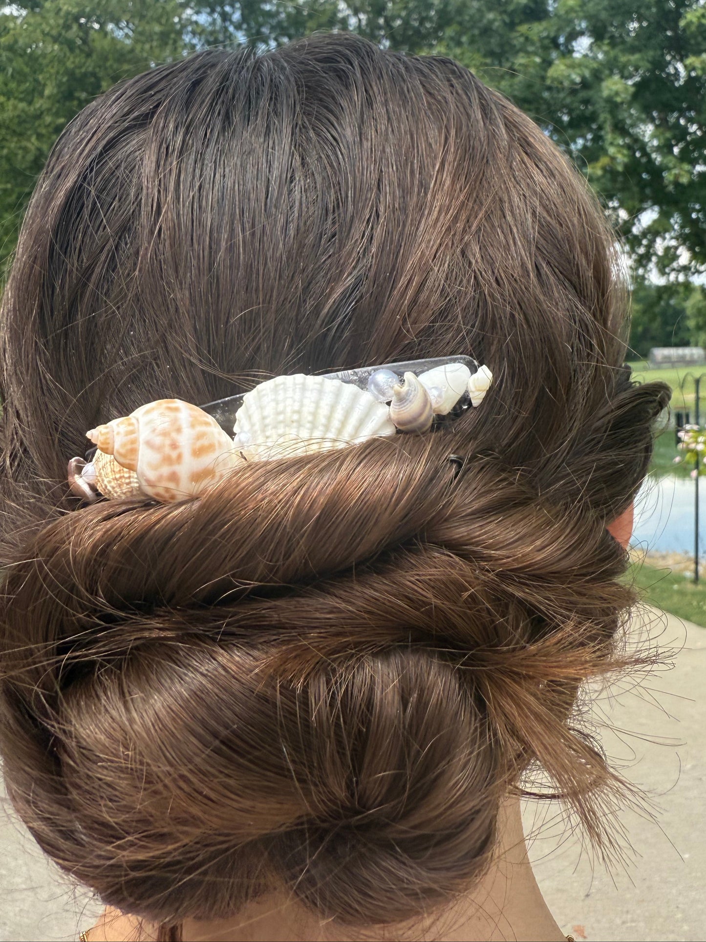 Close-up of a person's hair with a shell hair comb accessory outdoors