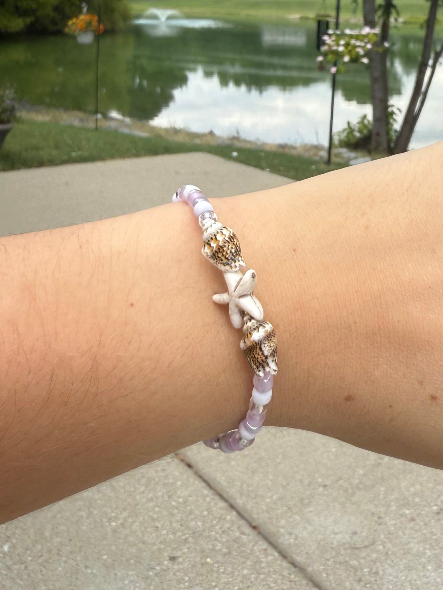 Hand wearing a bracelet with a blurred park background