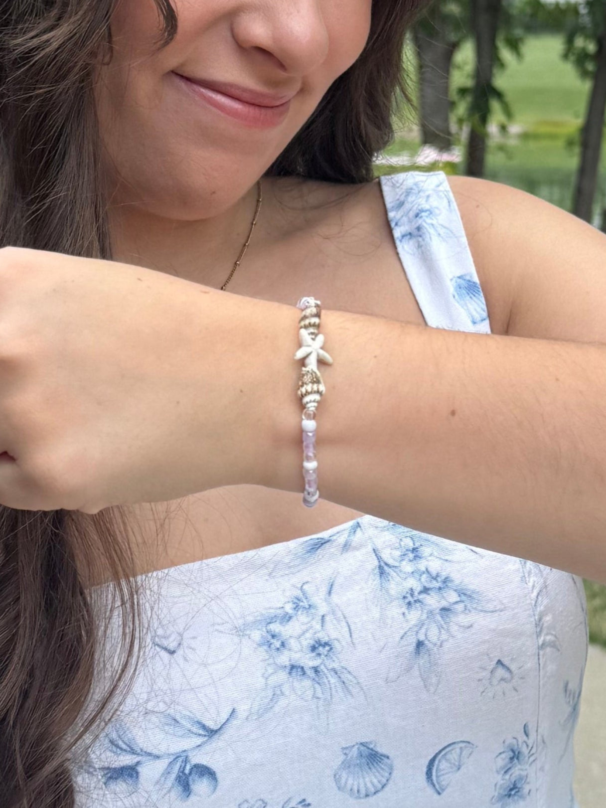 Woman wearing a seashell beaded bracelet with a scenic background