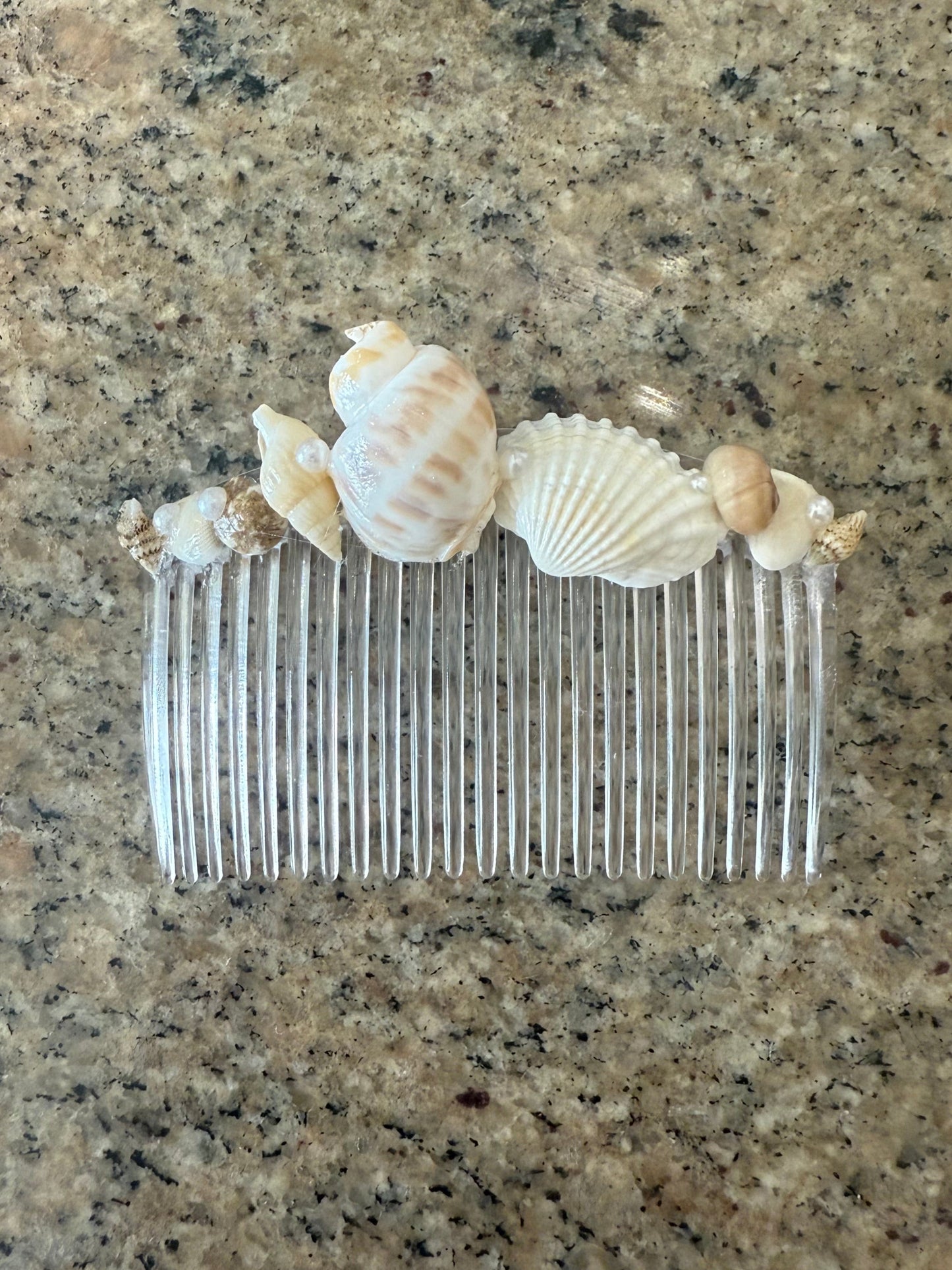 Clear comb with seashells on a speckled surface