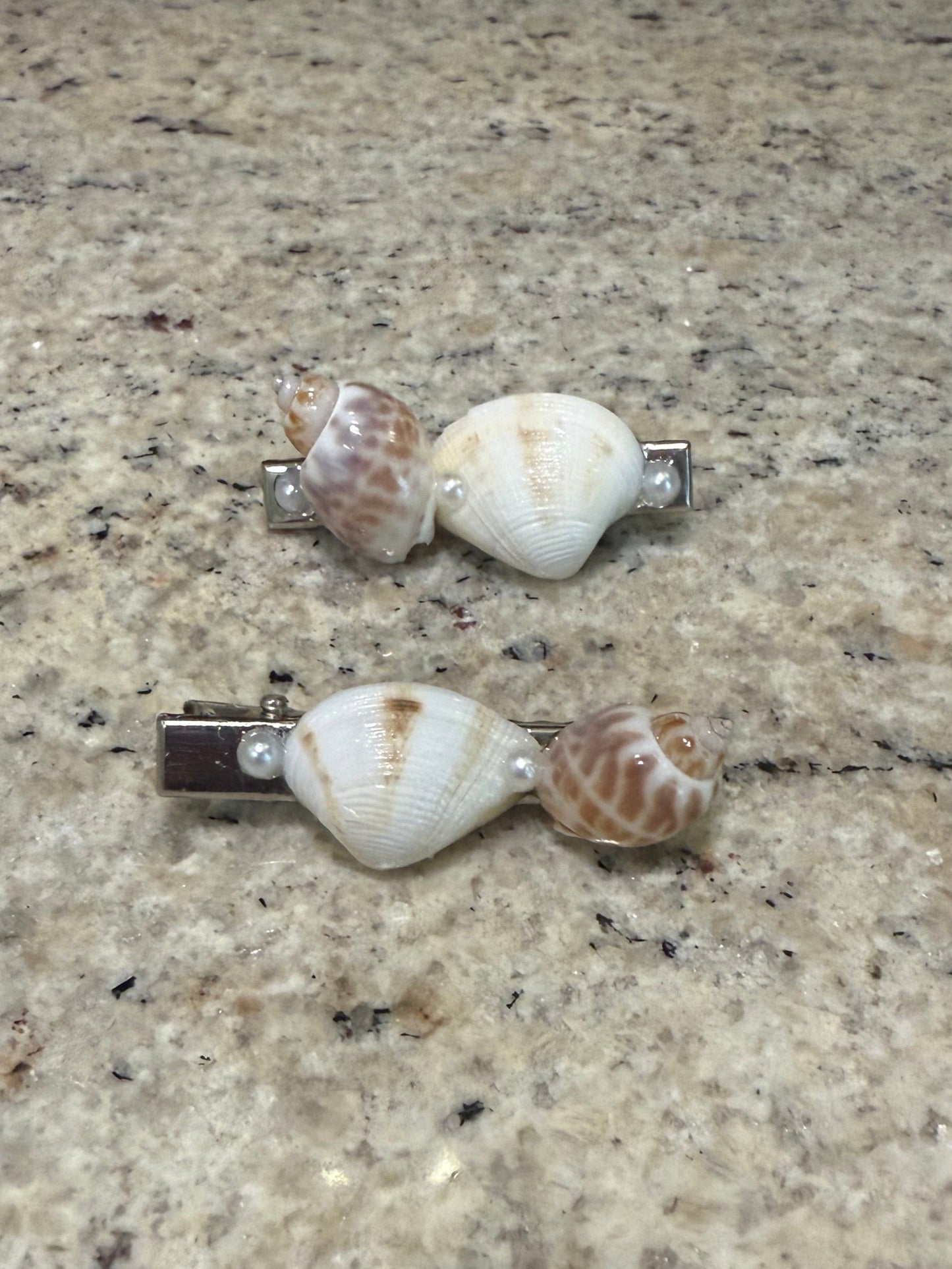 Shell-shaped hair clips on a textured surface