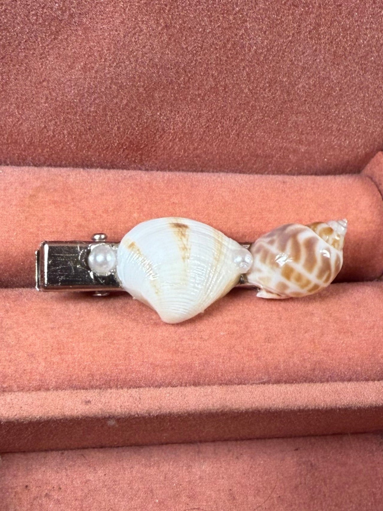 Shell-shaped hair clip on a pink cushion