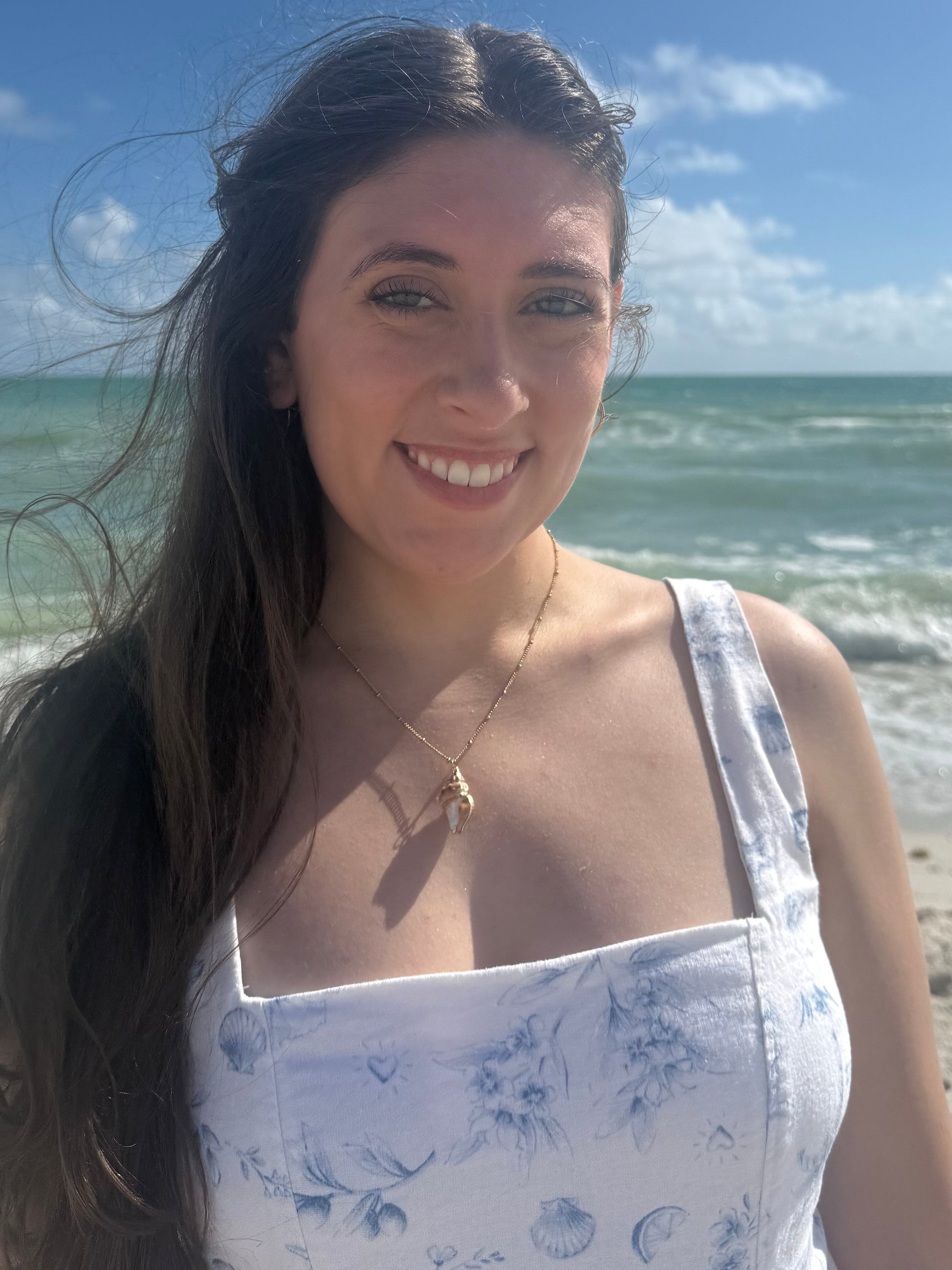 woman wearing a seashell necklace on a beach