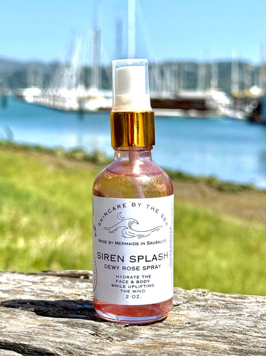 Bottle of 'Siren Splash' spray on a wooden surface with a scenic background