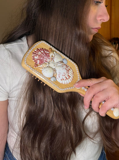 Person brushing their hair with a decorative brush in a bathroom setting