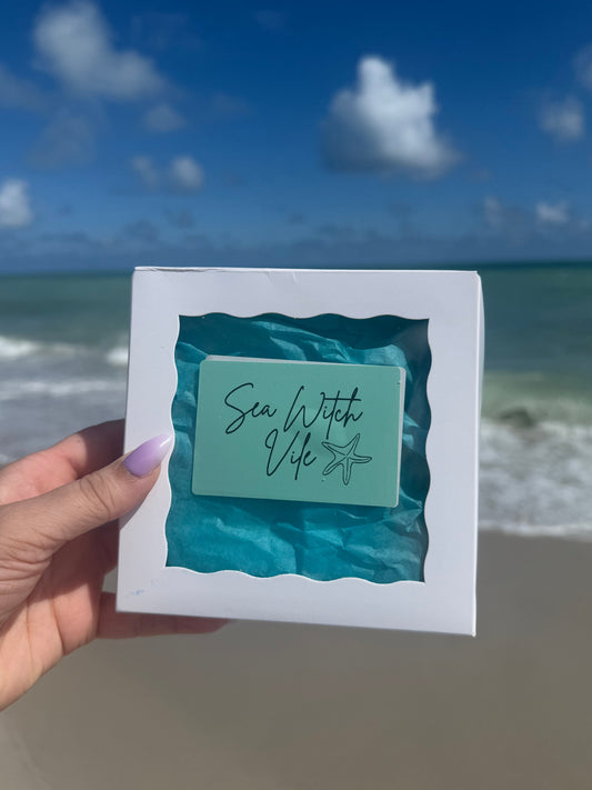 hand holding a sea witch vile spell bo on a beach with sky sand and ocean background