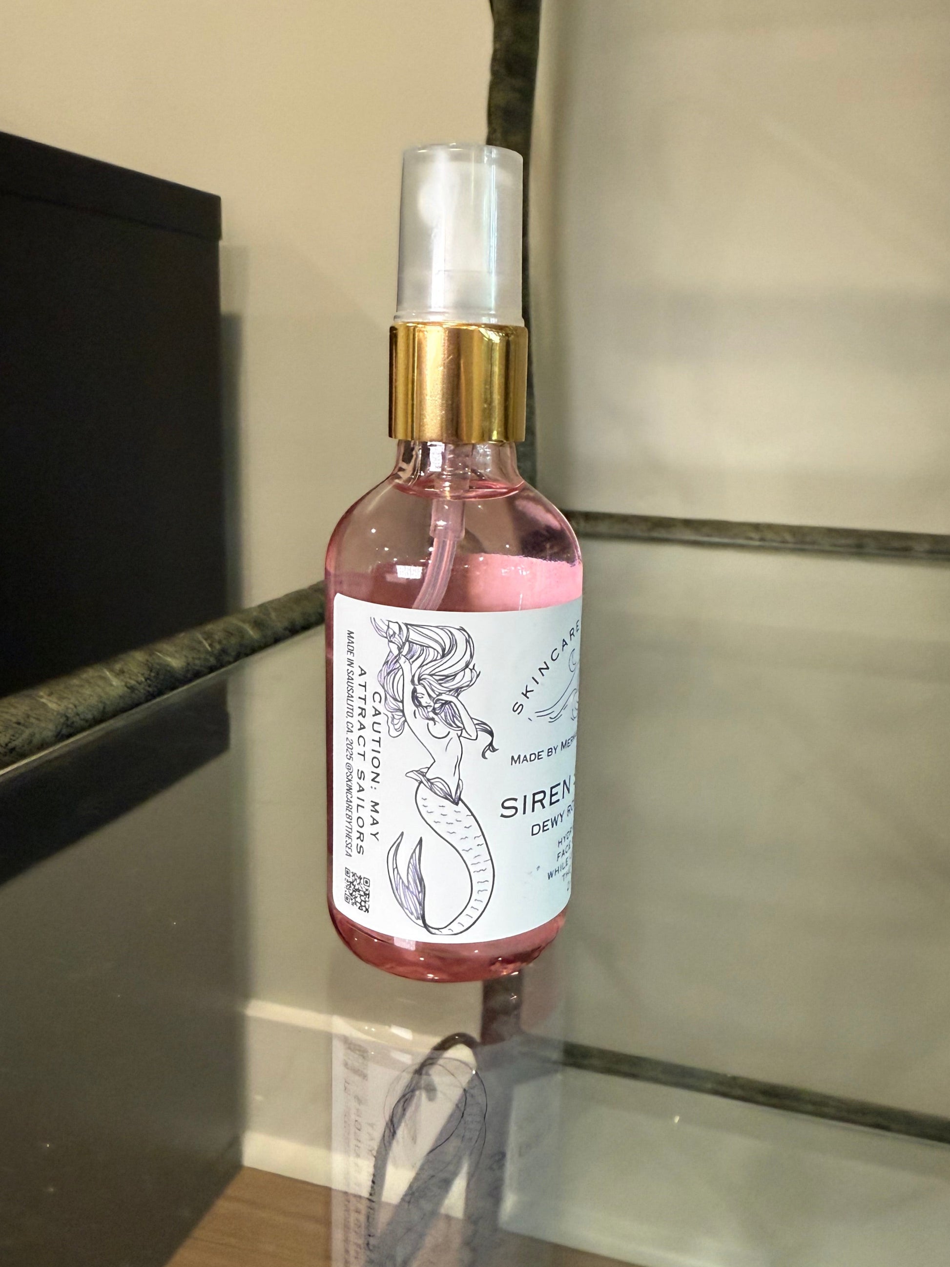 Small bottle of 'Siren Splash' showing the mermaid on the label label on a reflective surface