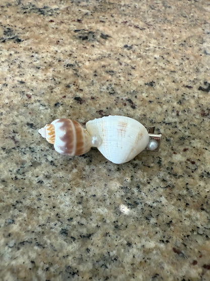 Seashell hair clip on a textured beige surface