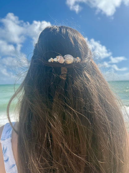 Seashell hair comb in woman's hair with beach ocean sky background
