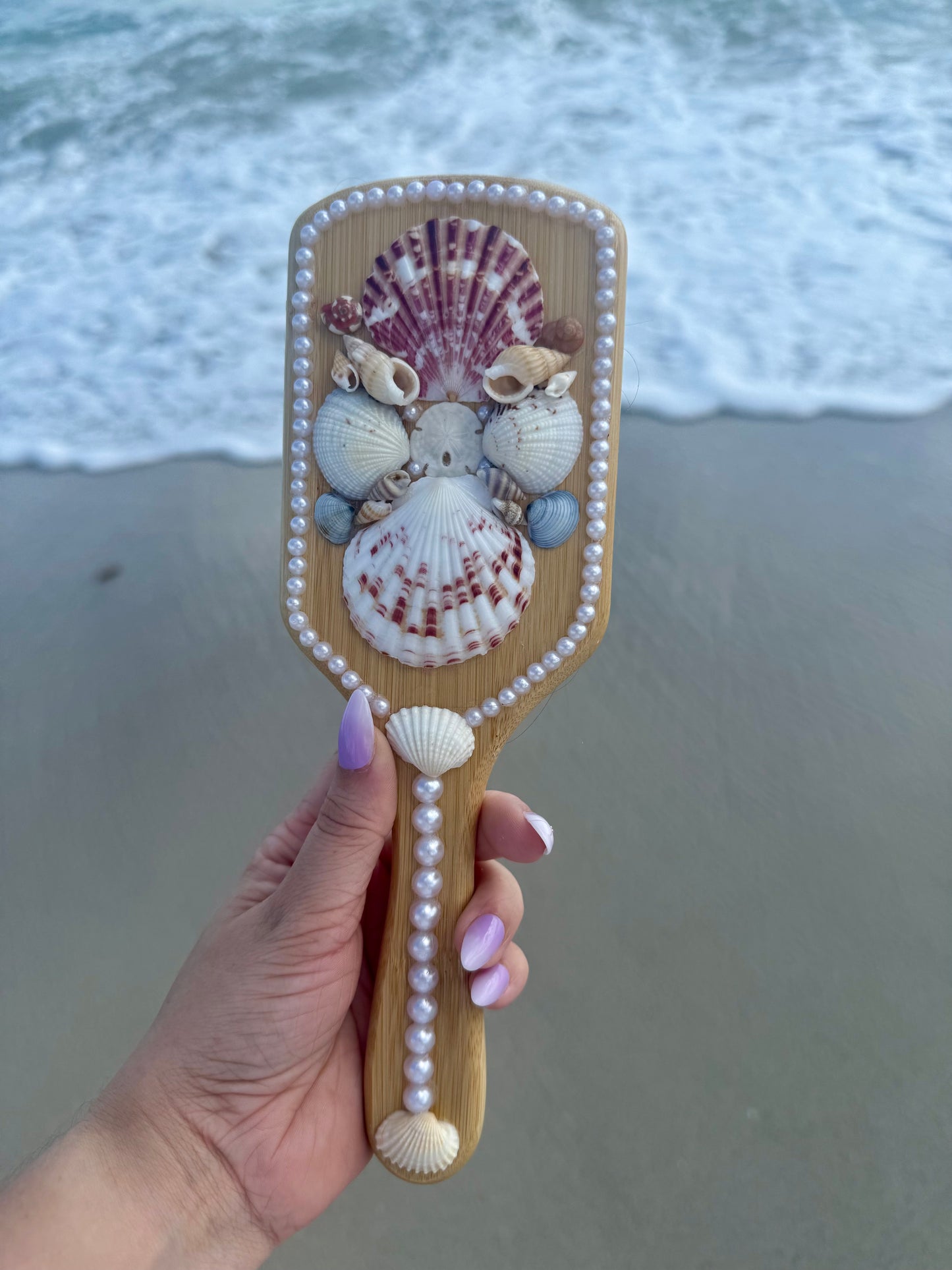 hand holding a mermaid seashell hairbrush