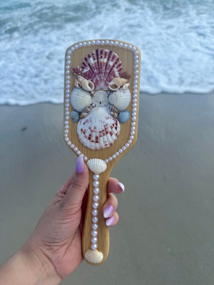 hand holding a mermaid seashell hairbrush