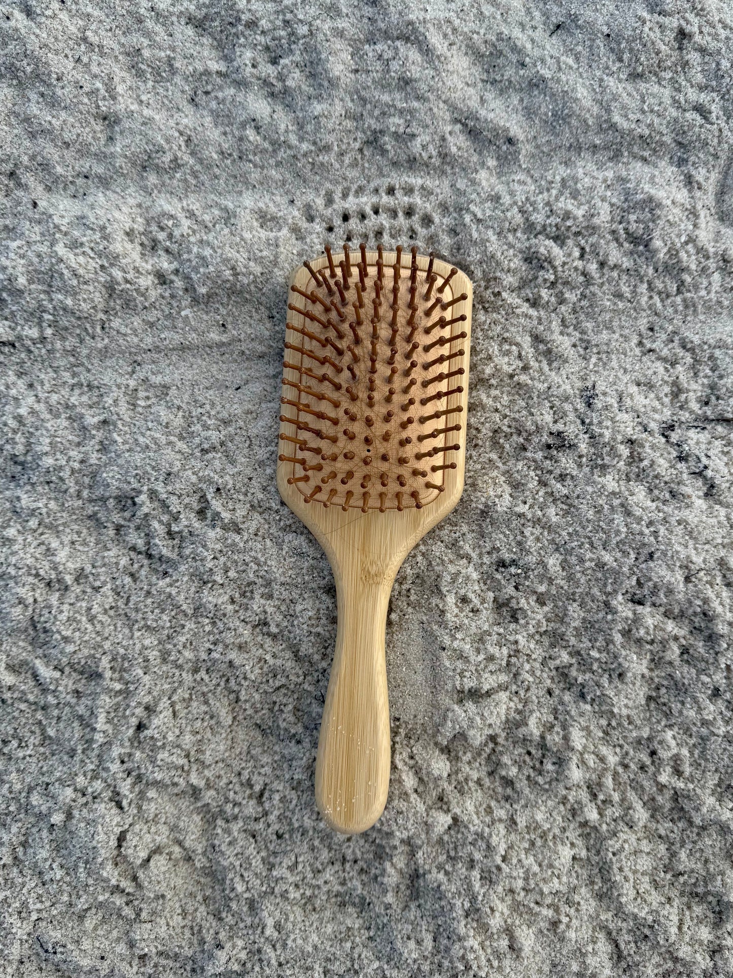Bamboo hairbrush on a sandy beach background