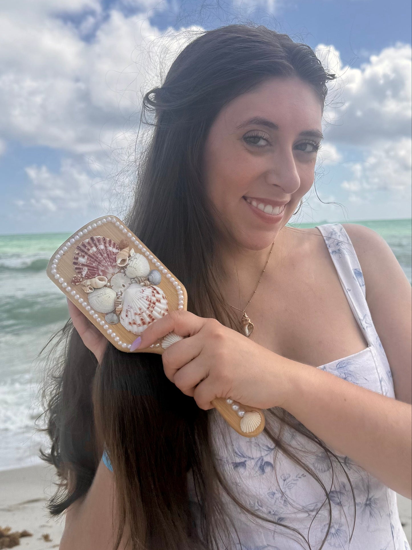 Woman holding a decorative shell hairbrush on a beach