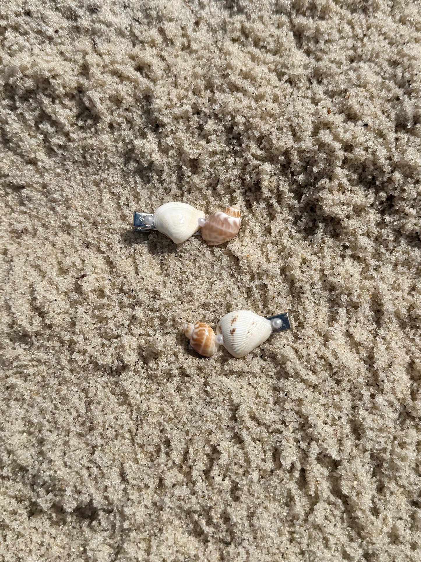 2 seashell hair clips on the sand