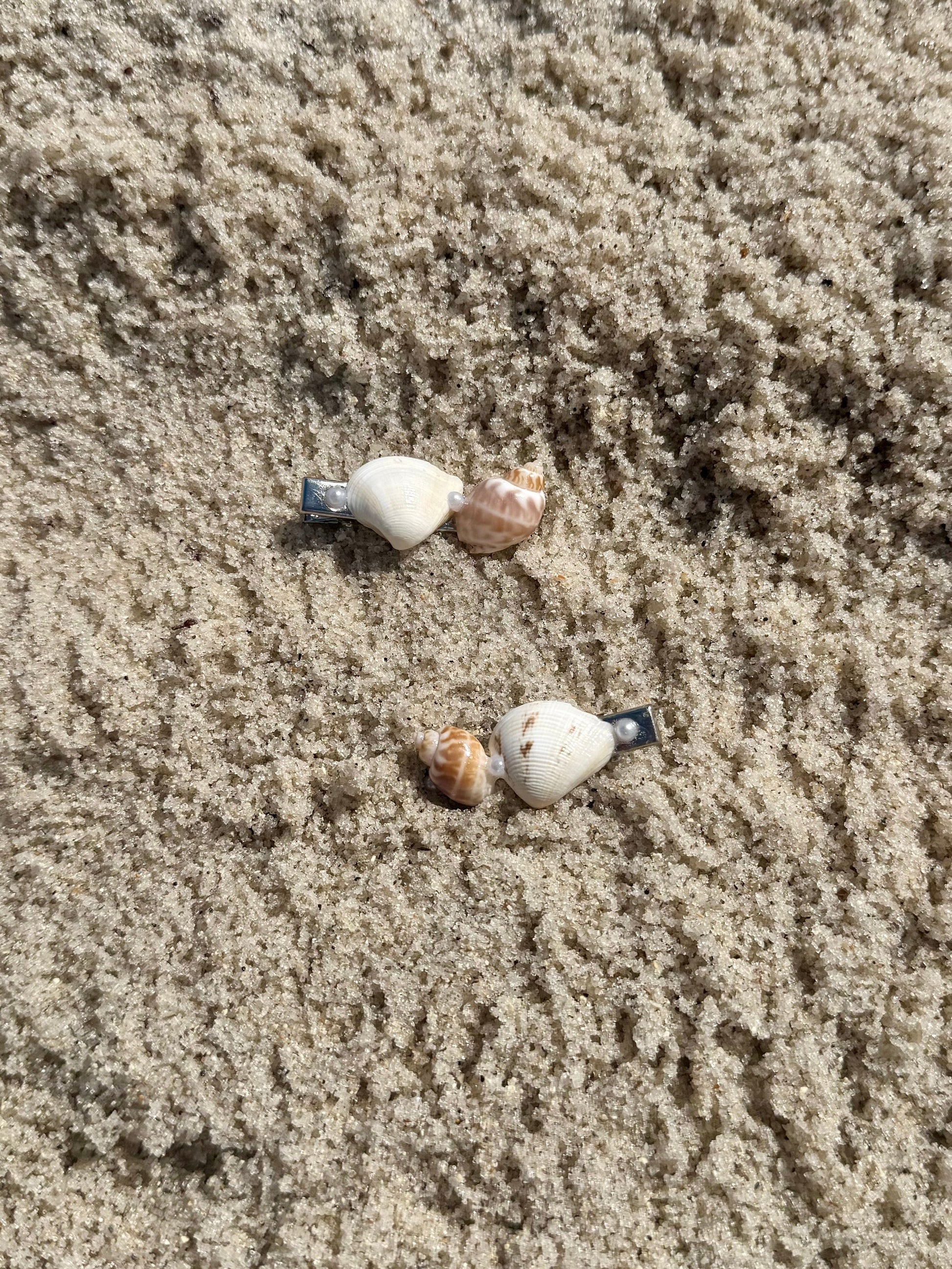 2 seashell hair clips on the sand
