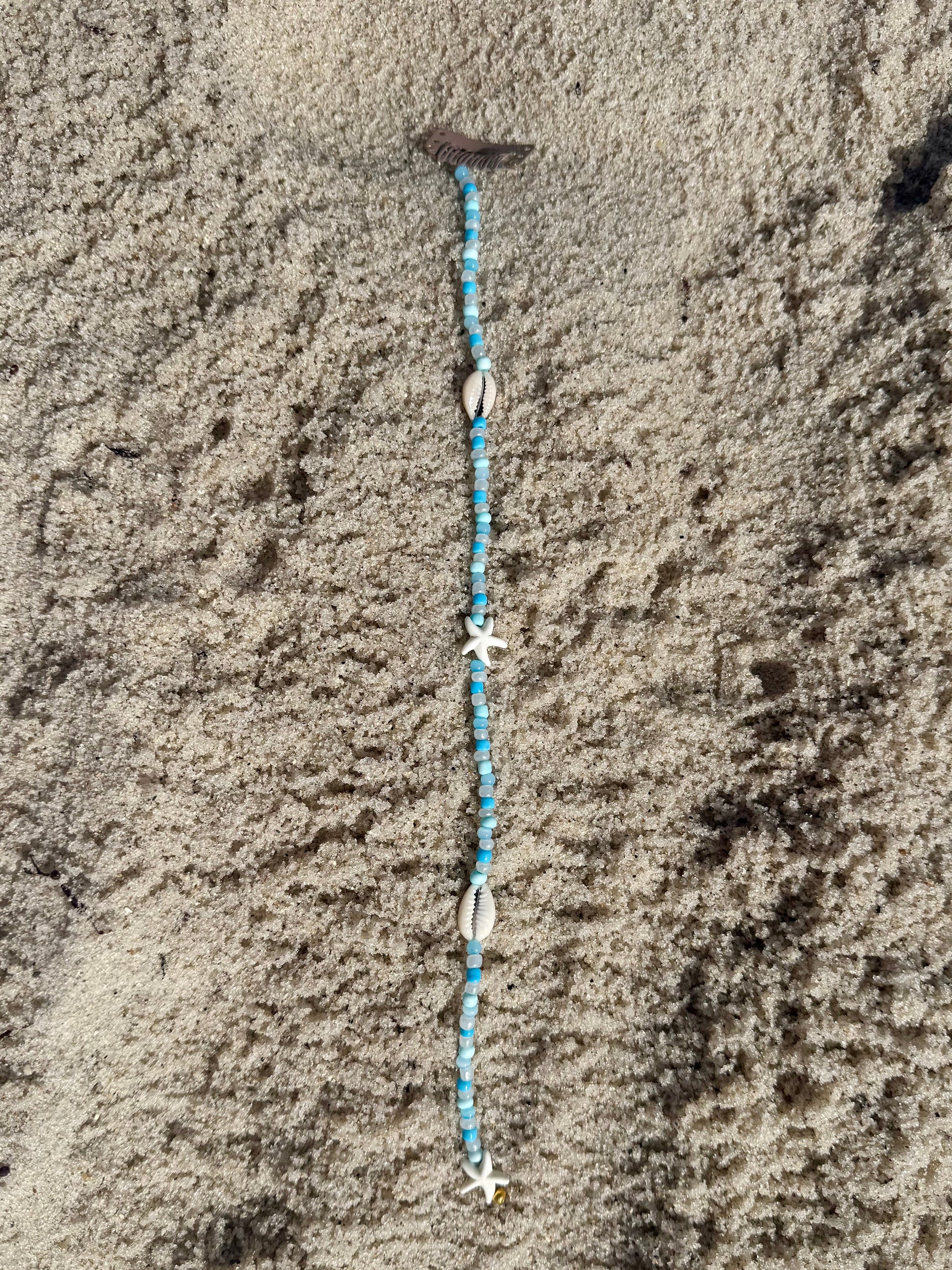 beaded seashell hair extension clip on sandy background