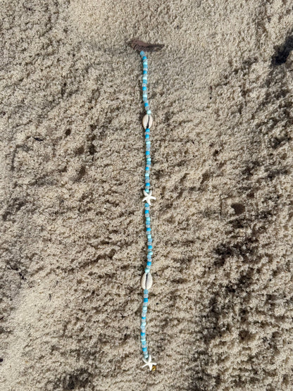 beaded seashell hair extension clip on sandy background