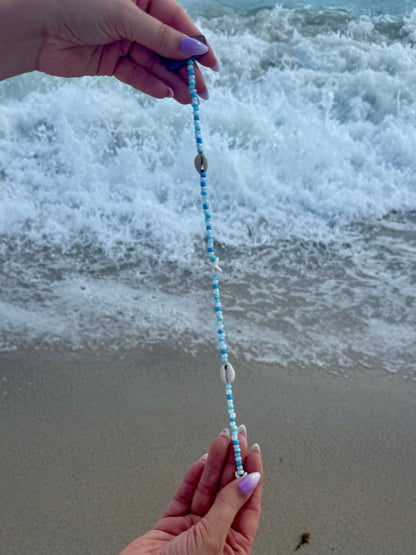 holding beaded seashell hair extension clip with beach background