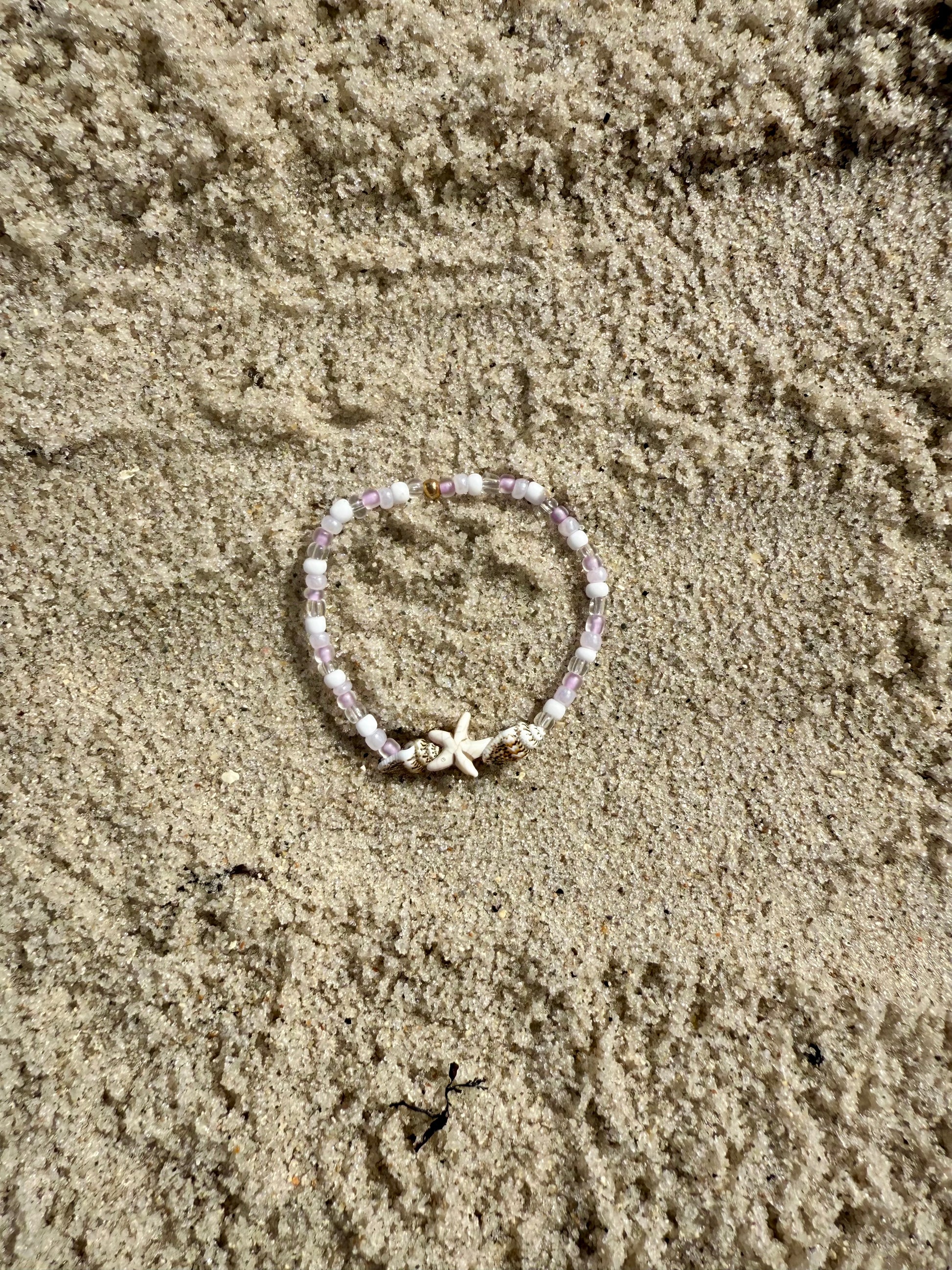 Bracelet with starfish charm on sandy surface