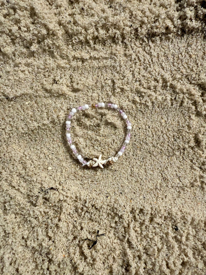 Bracelet with starfish charm on sandy surface