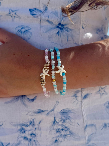 Close-up of a wrist wearing multiple beaded bracelets on a floral fabric background