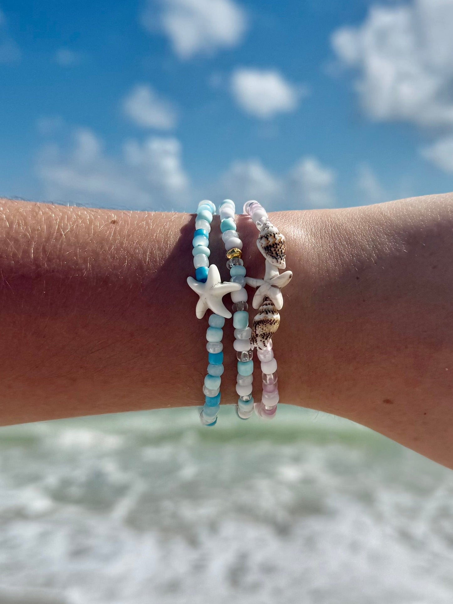 Seashell Bracelets on a woman's arm with beach sky sand water background