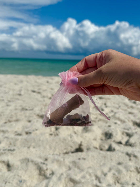 hand holding finished self-love spell pouch with sandy beach sky background