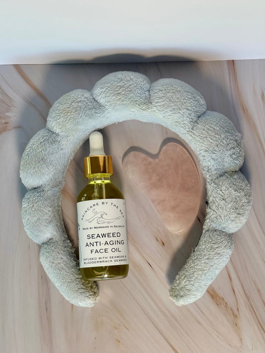 Flatlay of seaweed anti-aging face oil with guasha and headband to show skincare routine