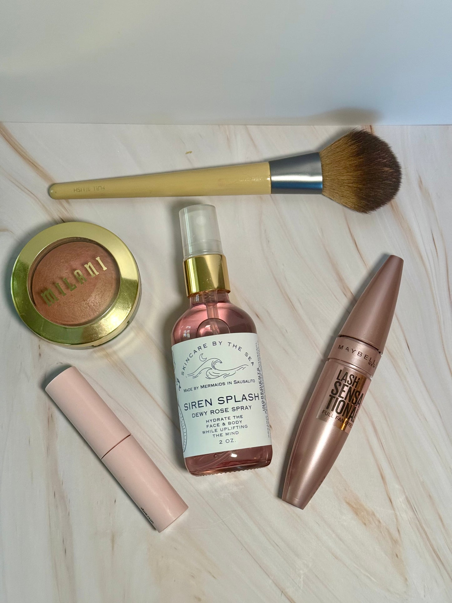 'Siren Splash' Rose spray Makeup setting spray displayed with makeup products. 