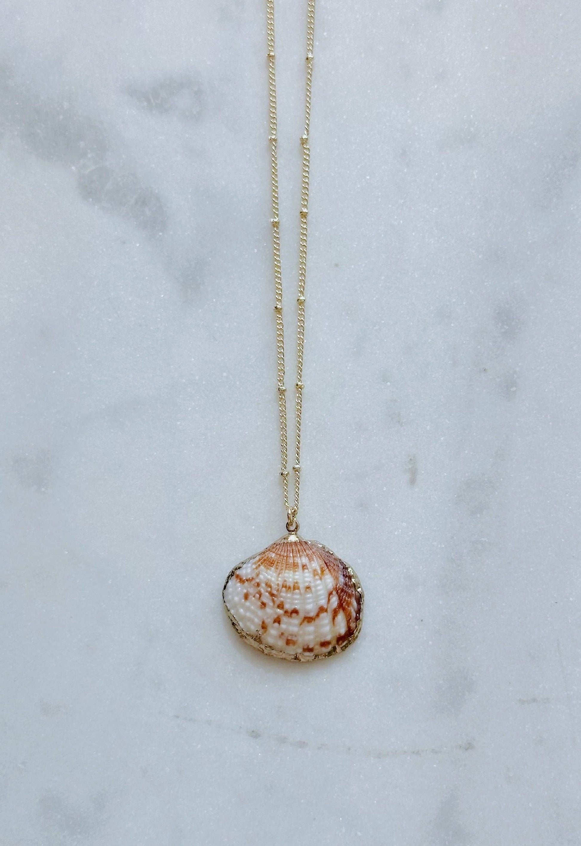 Necklace with a shell pendant on a marble surface